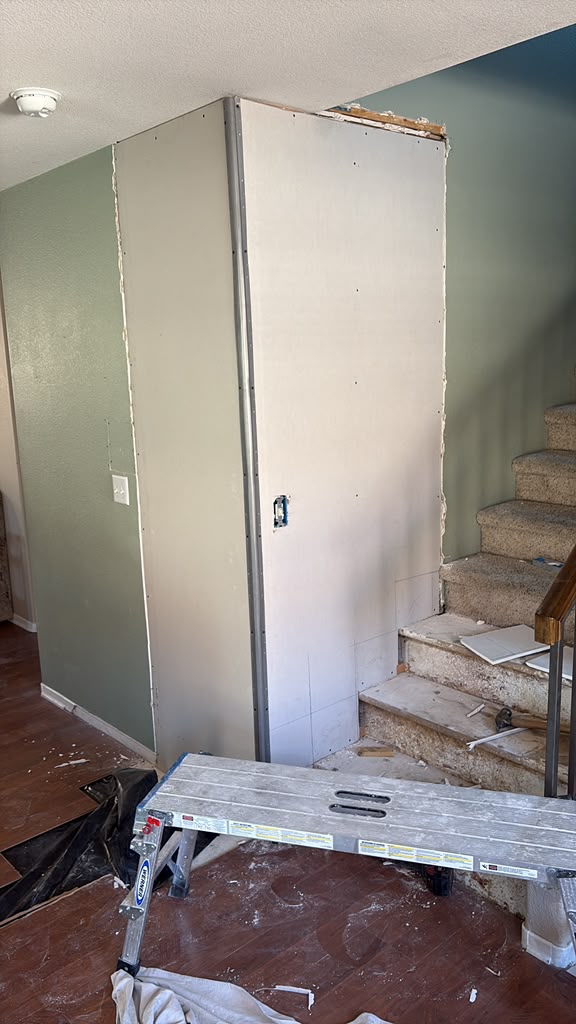 Fresh drywall hung on the new stair-side wall